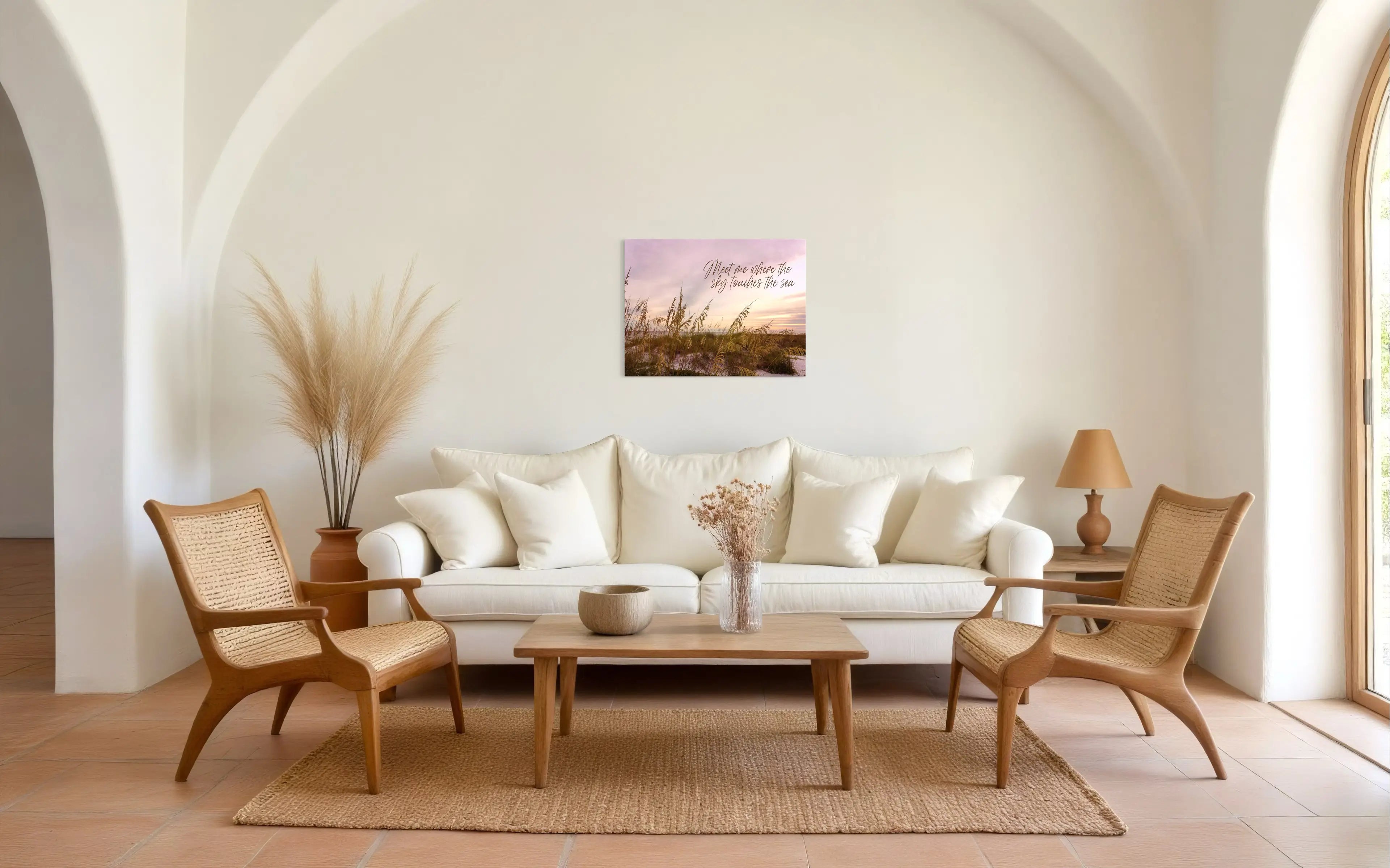 Bright coastal living room with natural rattan chairs, jute rug, and a recycled glass wall print reading ‘Meet me where the sky touches the sea,’ styled in sustainable, eco-coastal décor.