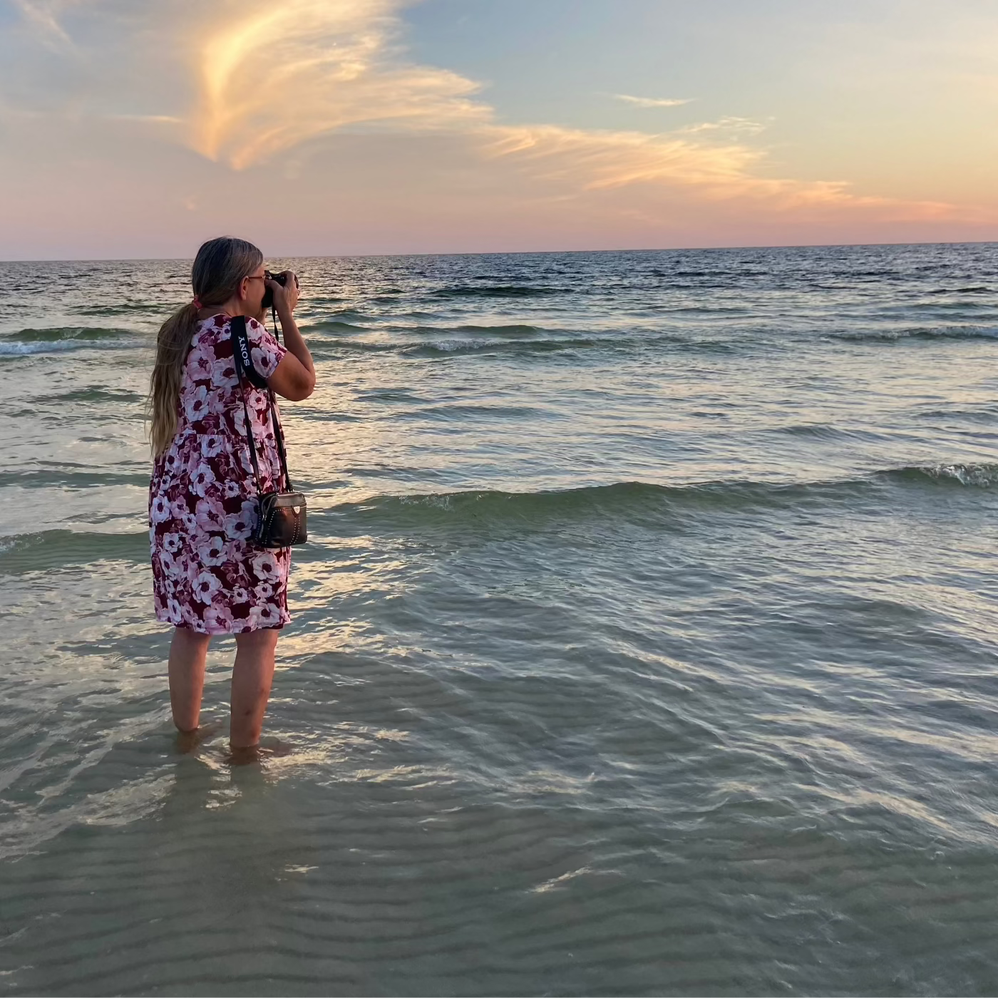 Echoes of the Sea photographer standing in Gulf photographing a heron in the setting sun.