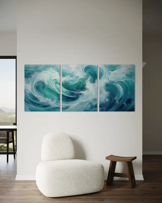 Abstract ocean wave triptych glass wall art above a neutral chair and side table in a modern coastal living room