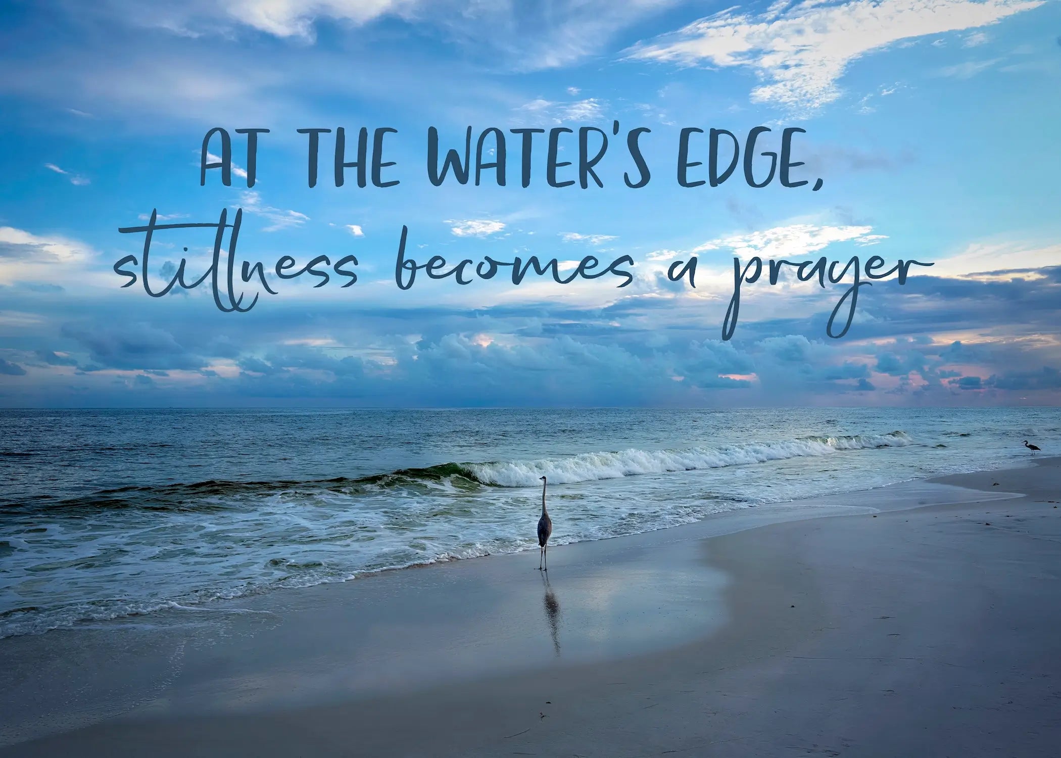 At the water’s edge, stillness becomes a prayer" heron coastal glass wall art print — inspirational ocean quote décor for beach homes.