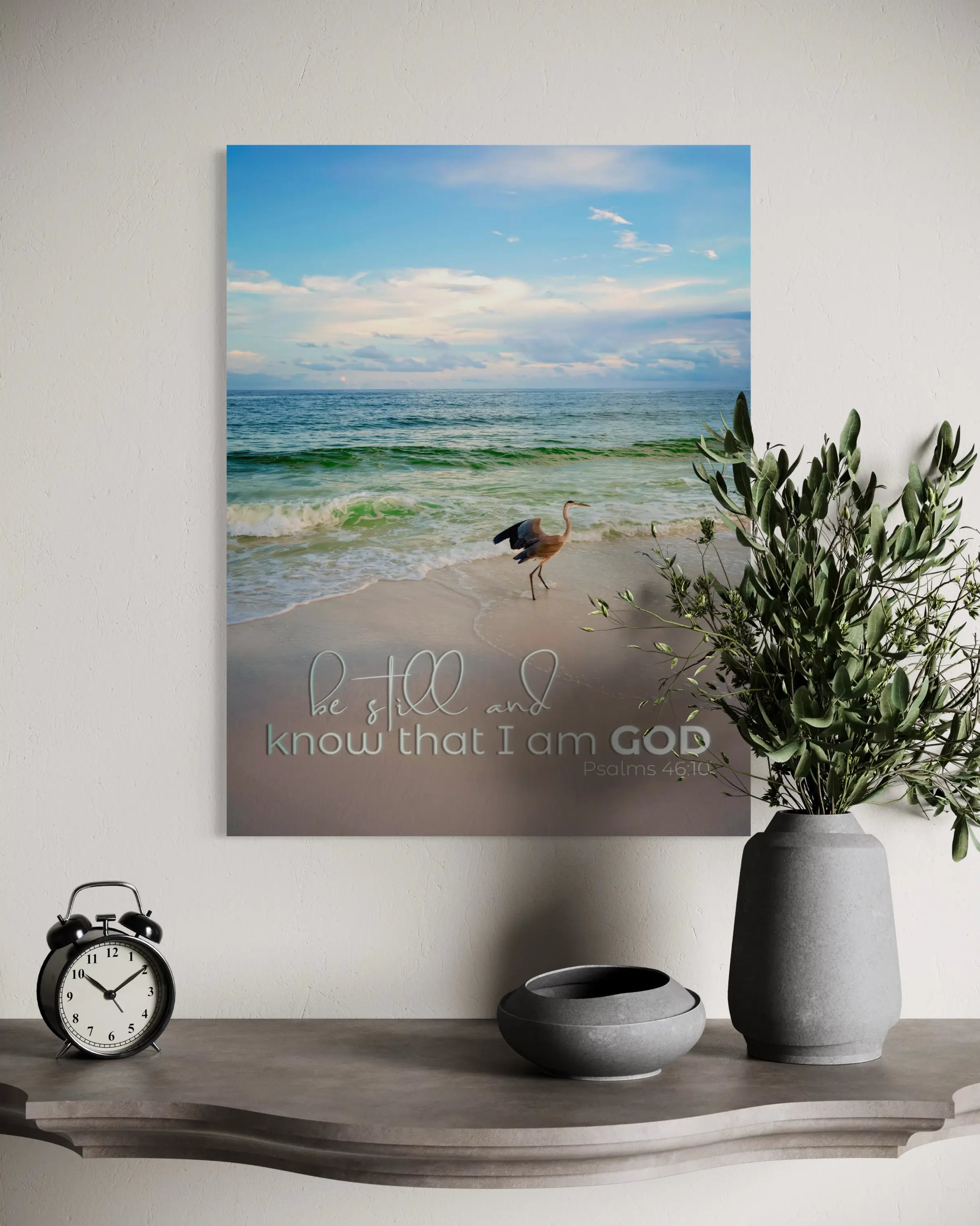 Inspirational heron coastal glass print with Psalm 46:10 scripture, displayed above a decorative shelf in a peaceful coastal home,