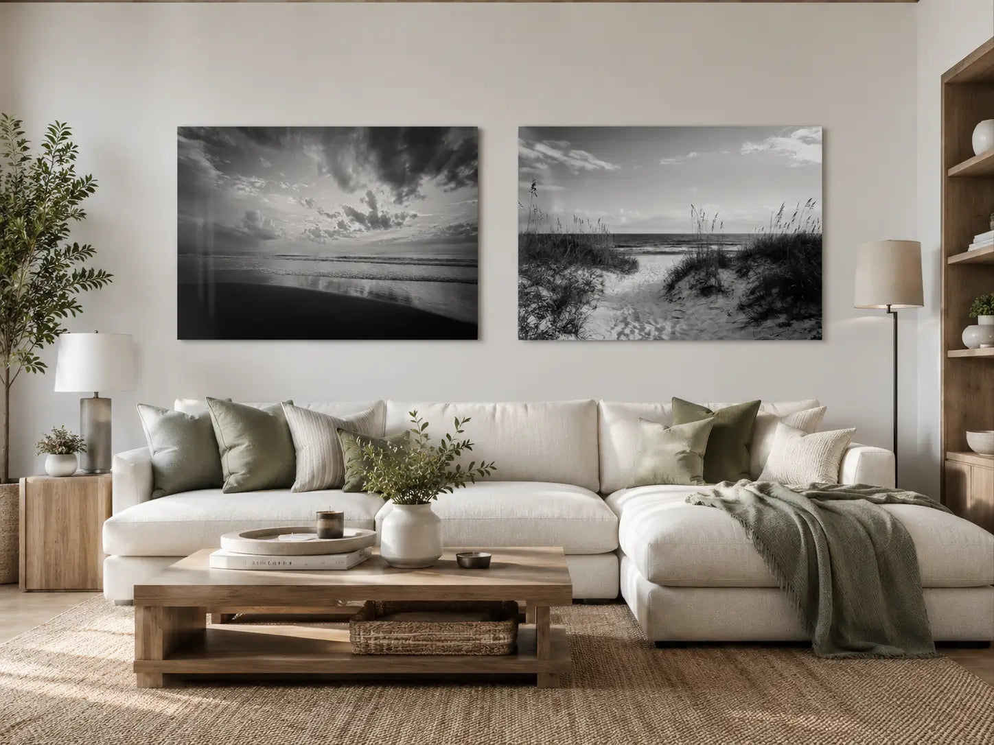 Two black-and-white coastal glass prints showing ocean surf and a sandy dune path above a cream sectional in a warm modern coastal living room.