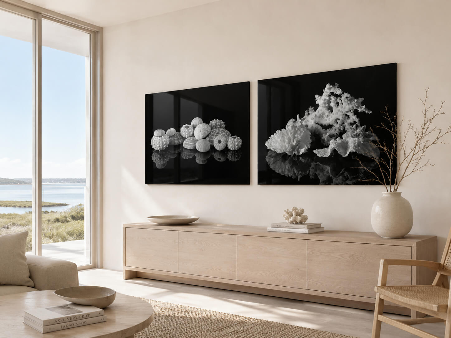 Light-filled coastal room with marsh view and two black-and-white glass wall art prints featuring sea urchin shells and coral on a pale neutral wall.