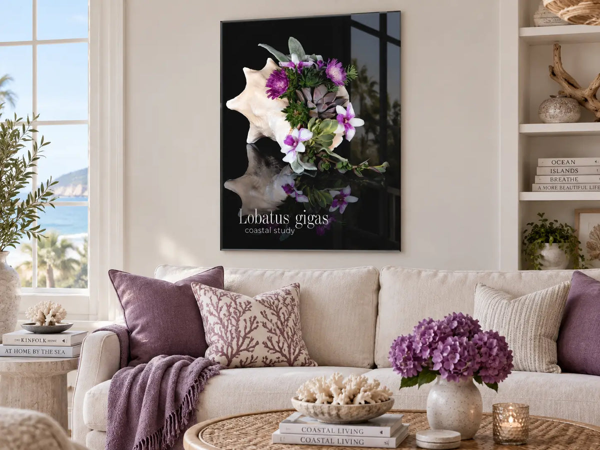 Conch shell and succulent coastal study glass print displayed above a sofa in a refined coastal living room.