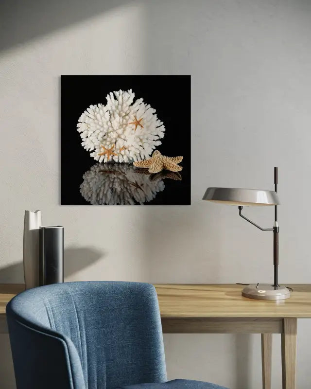Coastal glass print of white coral and golden starfish on black background displayed above a desk.