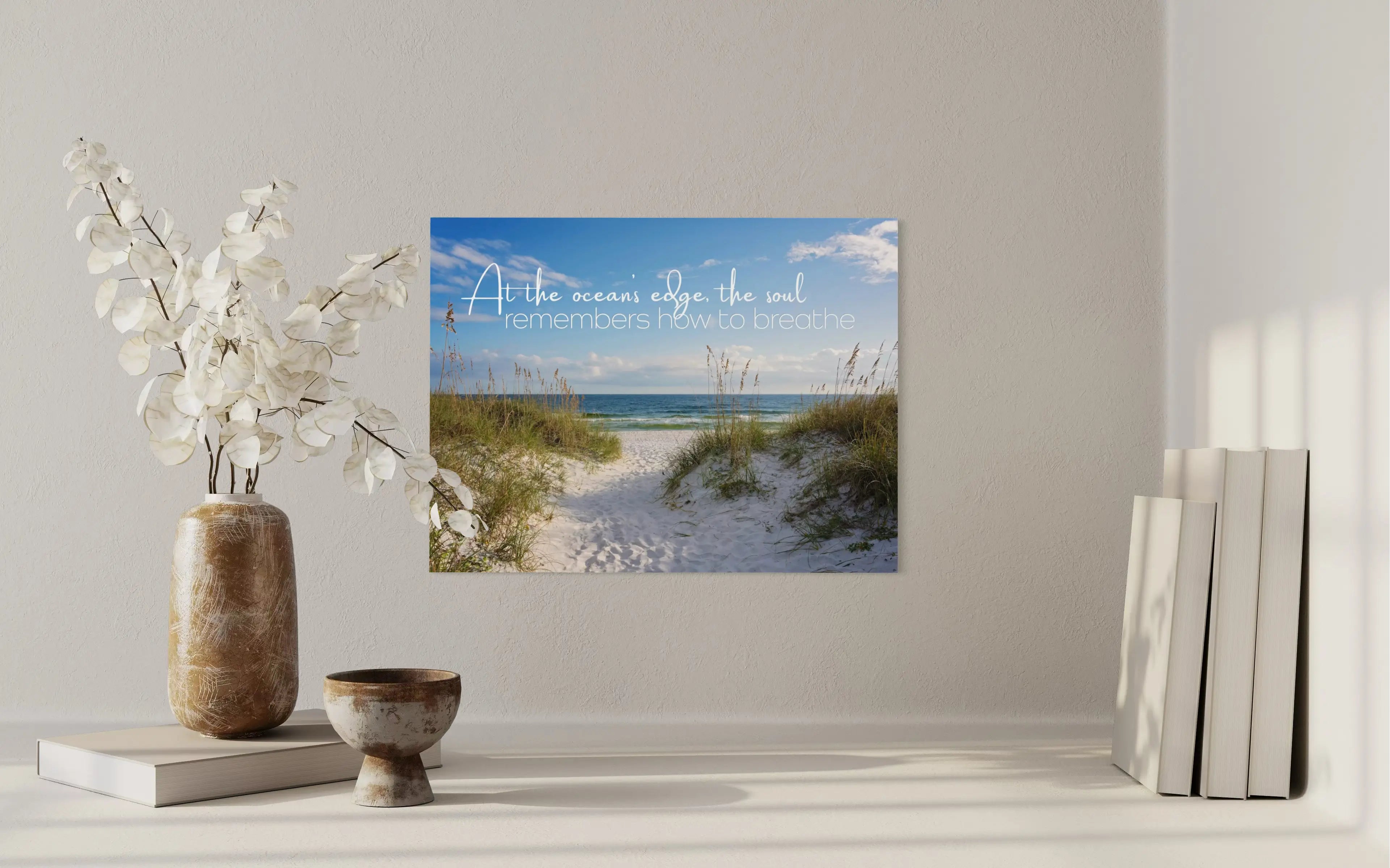 Coastal glass print with inspirational quote: At the ocean’s edge, the soul remembers how to breathe. Sand dunes and sea oats above a shelf