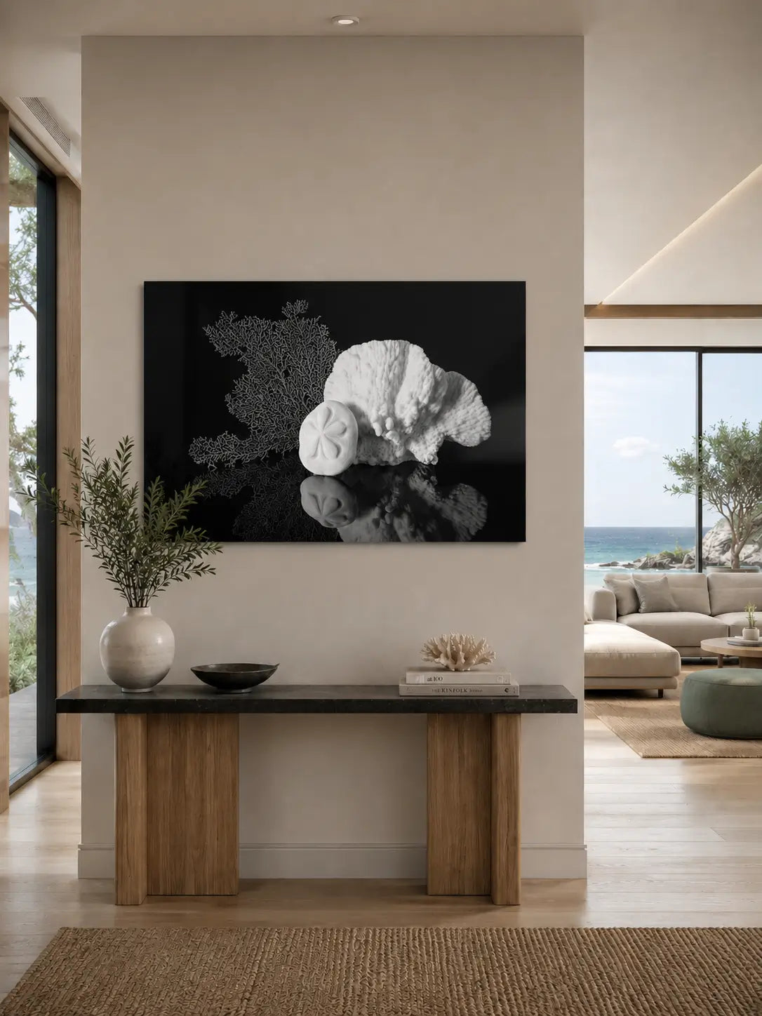 Black-and-white sea fan, sea biscuit, and Merulina coral glass wall art displayed above a wood console in a warm modern coastal entryway with an ocean view.