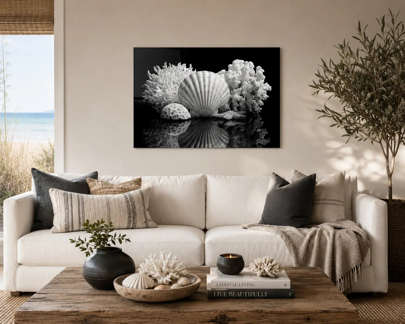Black-and-white seashell and coral glass wall art displayed above a white sofa in a warm modern coastal living room with charcoal accents.
