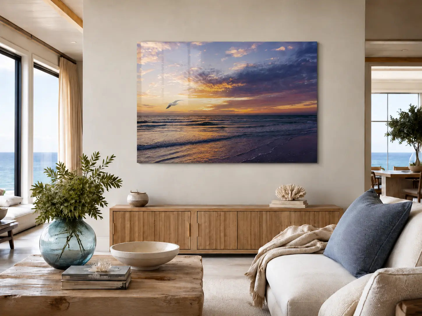 Coastal living room with a beach sunset glass print on the wall, featuring a couch, coffee table, and decorative items.
