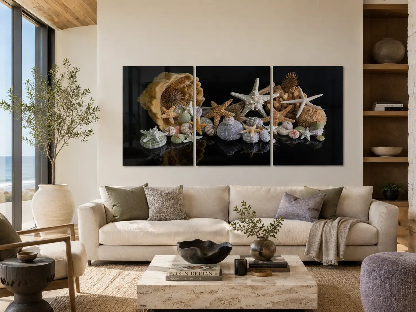 Starfish and sea urchin triptych glass wall art displayed above a cream sofa in a modern coastal living room with sage and lavender grey accents.