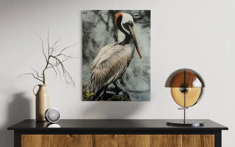 Glass print of brown pelican beside water with raindrop ripples on a stormy day-wall decor.