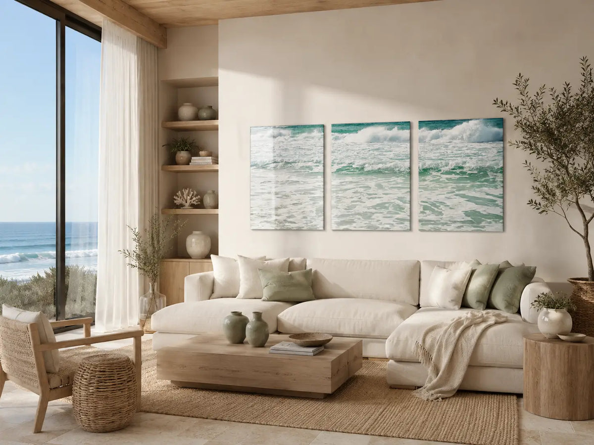 Biophilic coastal living room with ocean view, natural light, neutral furnishings, and a three-panel wave glass wall art print above a white sectional sofa.