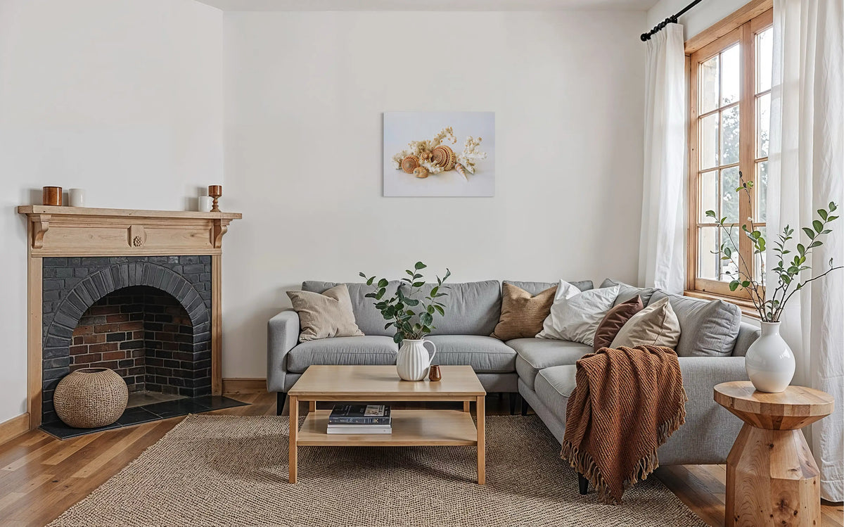 Coastal farmhouse living room with light wood fireplace, gray sofa, and seashell wall art.
