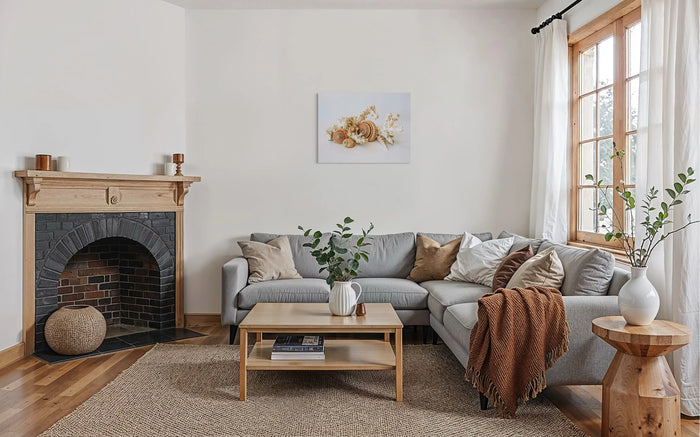 Coastal farmhouse living room with light wood fireplace, gray sofa, and seashell wall art.