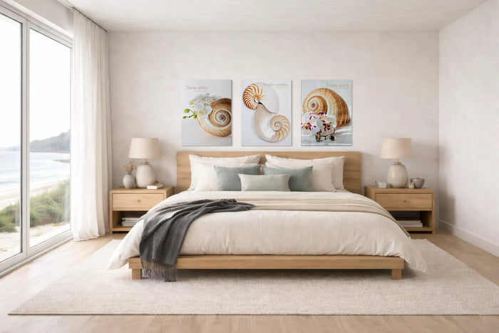 Modern coastal bedroom with three shell study and botanical glass posters displayed above a bed, styled in a light, refined interior with an ocean view.