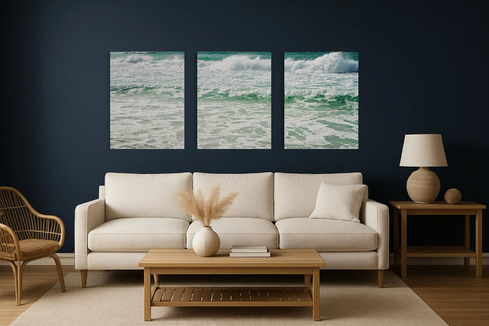 Coastal glass wall art triptych centered above cream sofa on navy wall, showing proper size and spacing over a living room couch