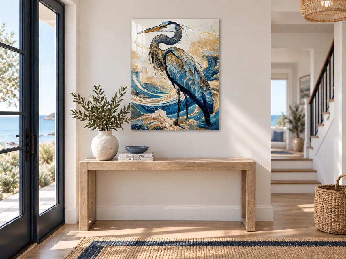 Heron glass wall art displayed above a light wood console in a restrained modern coastal entryway with navy and blue accents.