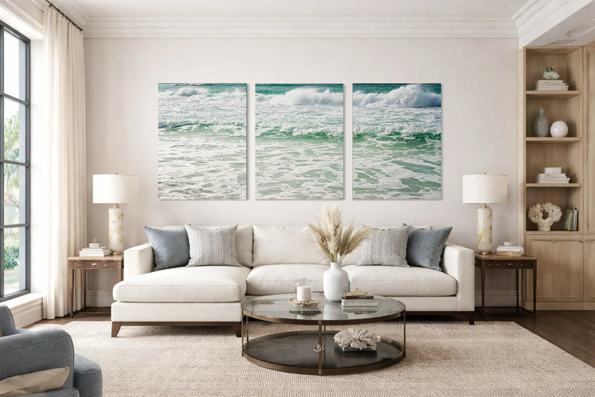 Coastal Luxury living room with symmetrical ocean wave triptych, ivory linen sectional sofa, marble and glass coffee table, sheer drapery, and soft resort-style neutral palette.