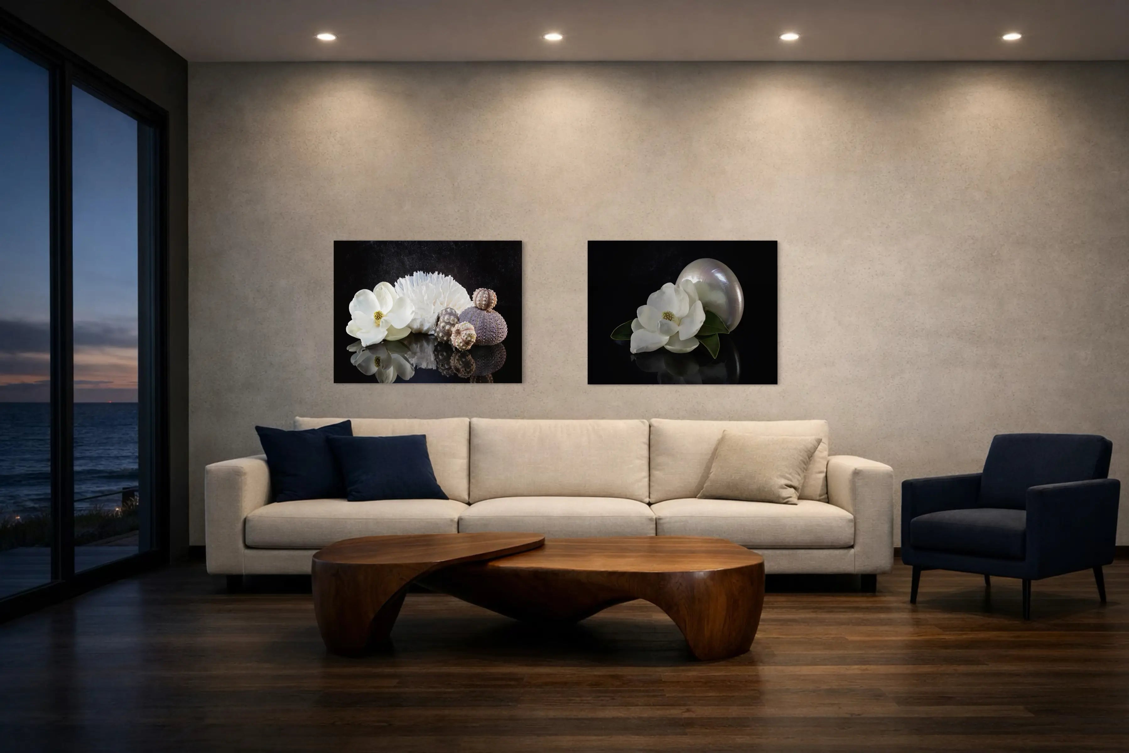 Modern moody coastal living room with neutral sofa, navy accents, walnut coffee table, and black-background seashell glass artwork displayed on a wall overlooking the ocean at dusk.