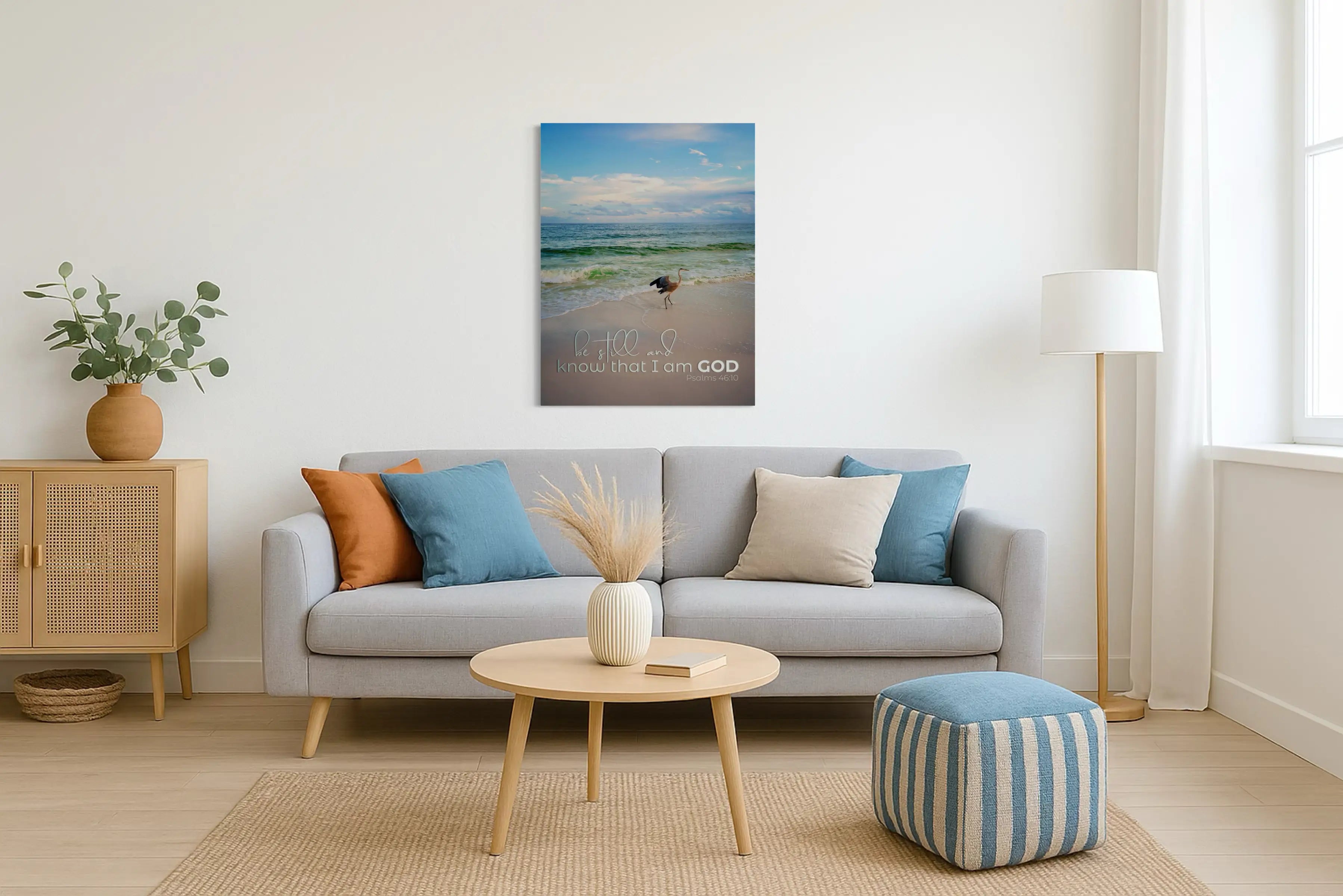 Inspirational heron coastal glass print with Psalm 46:10 scripture, displayed above a sofa in a coastal living room, Christian wall art bringing peace and faith to coastal home décor.