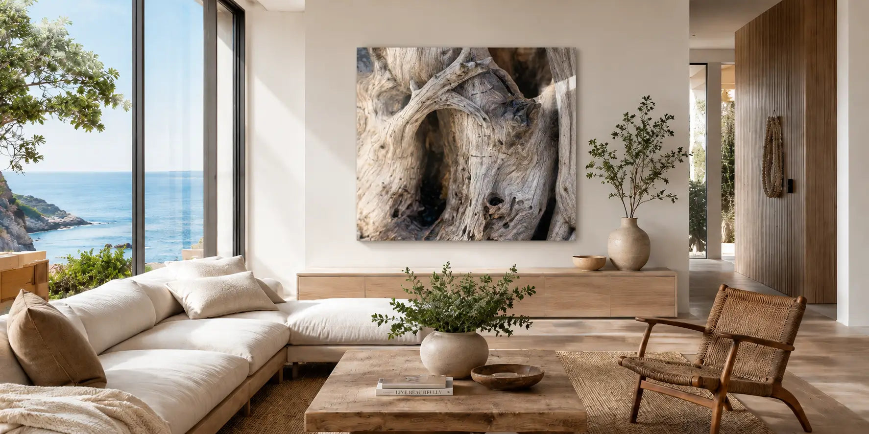 Light-filled coastal living room with ocean view and driftwood glass wall art, styled with pale wood, woven texture, and warm biophilic calm