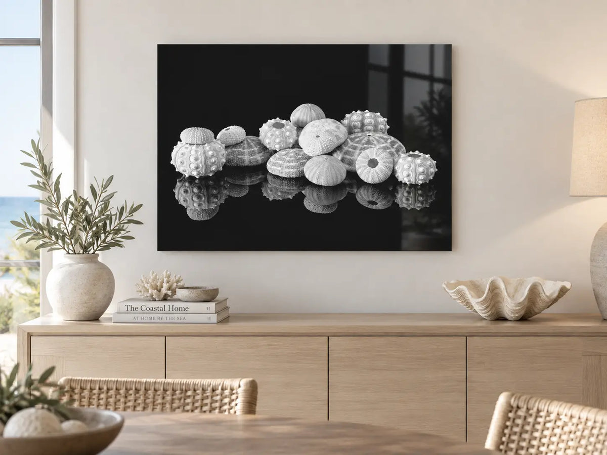 Black and white sea urchin glass print displayed above a modern coastal dining room sideboard.