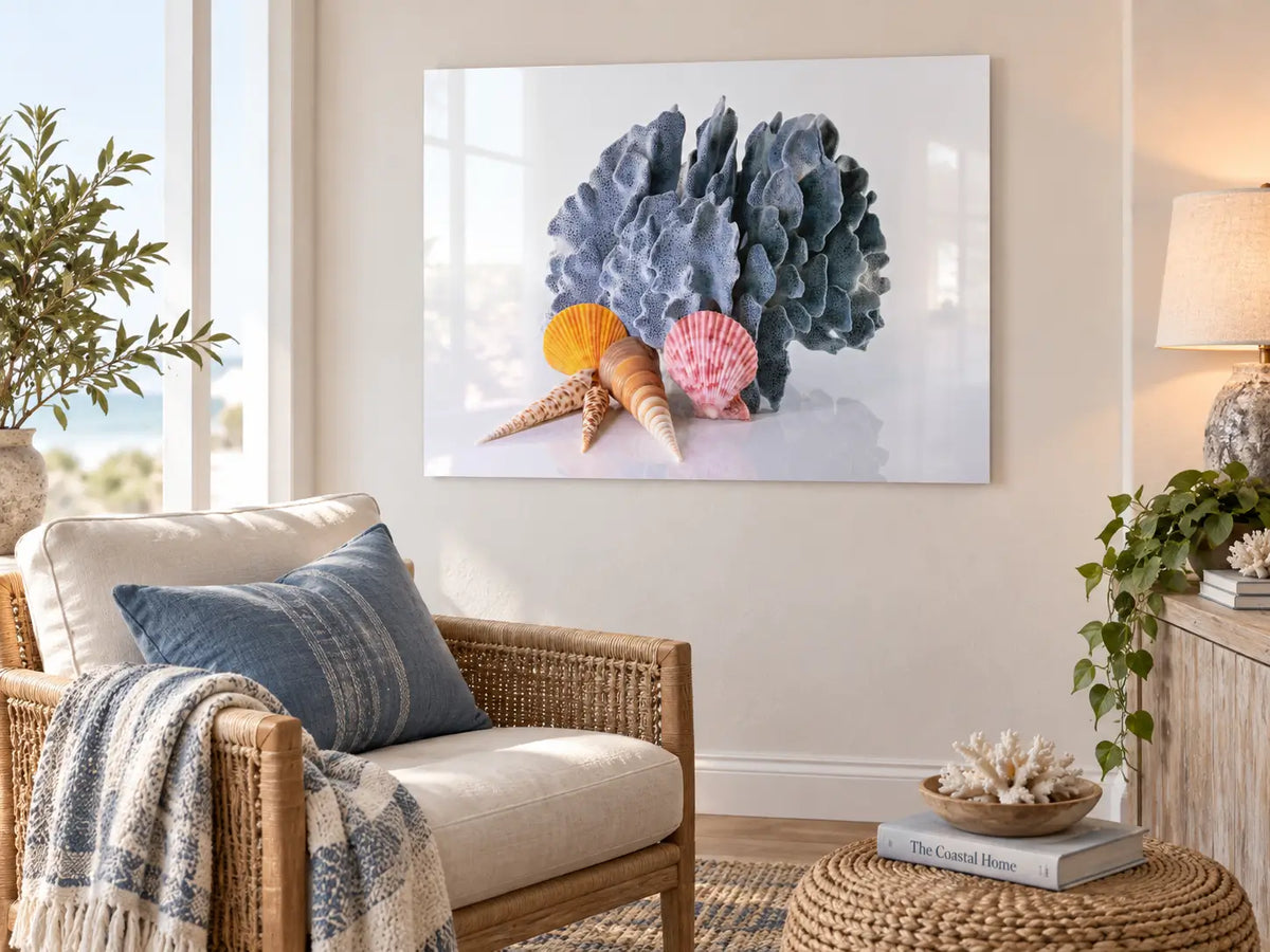 Blue Coral Seashells Coastal Glass Print displayed in a cozy modern coastal reading nook with light seating, layered textures, and airy beach-inspired decor.
