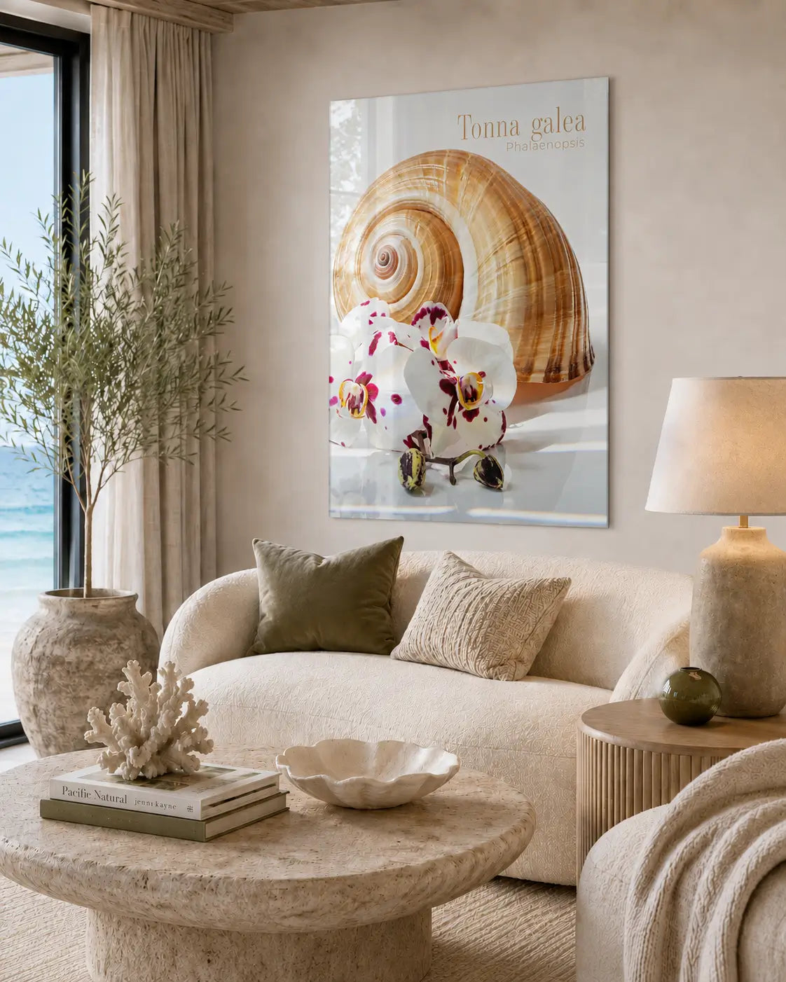 Neutral coastal living room with a curved cream sofa, soft natural textures, and a glossy frameless glass print of a spiral shell and white orchids mounted above the seating area.