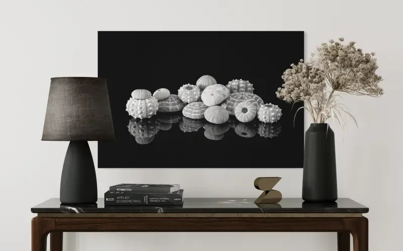 Monochrome sea urchins on reflective black background, coastal glass print shown above table.