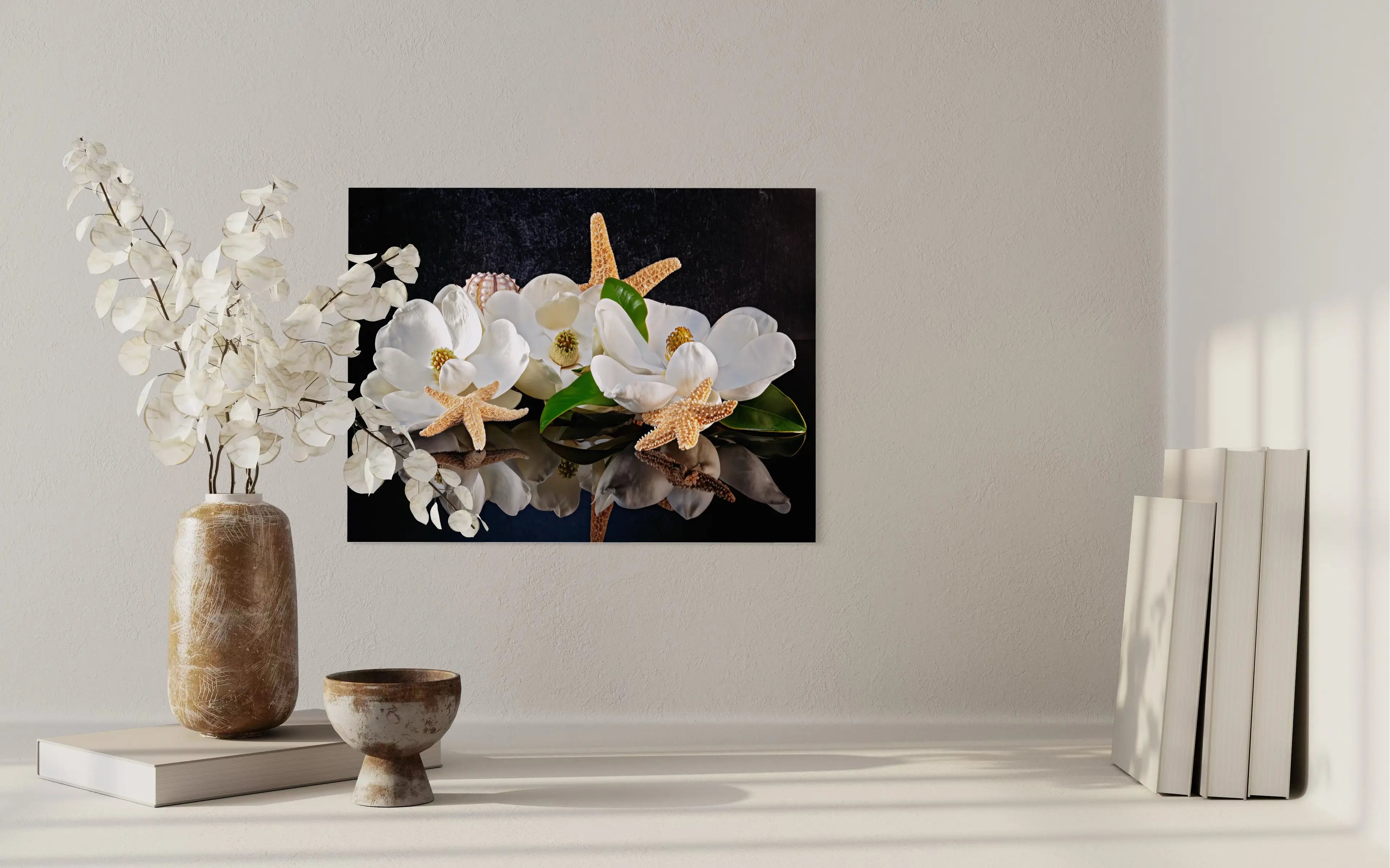 Glass print of 3 magnolia blossoms, starfish and sea urchins on reflective black background.