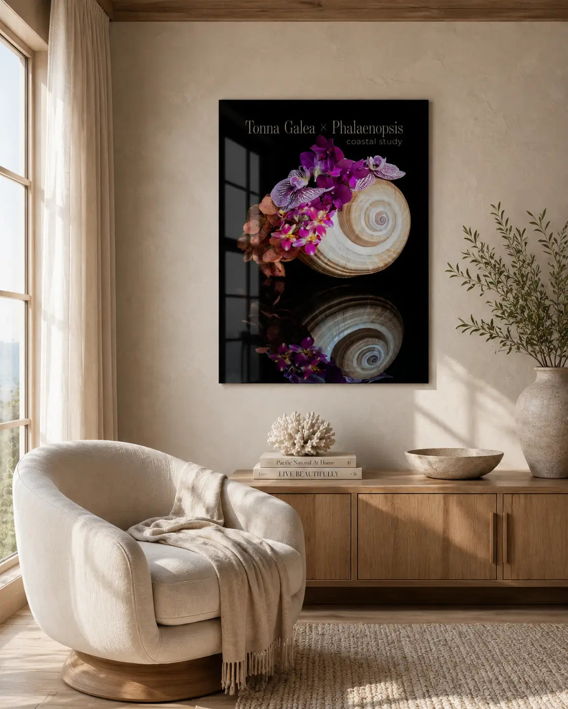 High-end neutral coastal sitting area with a curved cream chair and a glossy frameless glass print of a spiral shell with vivid purple orchids mounted above.