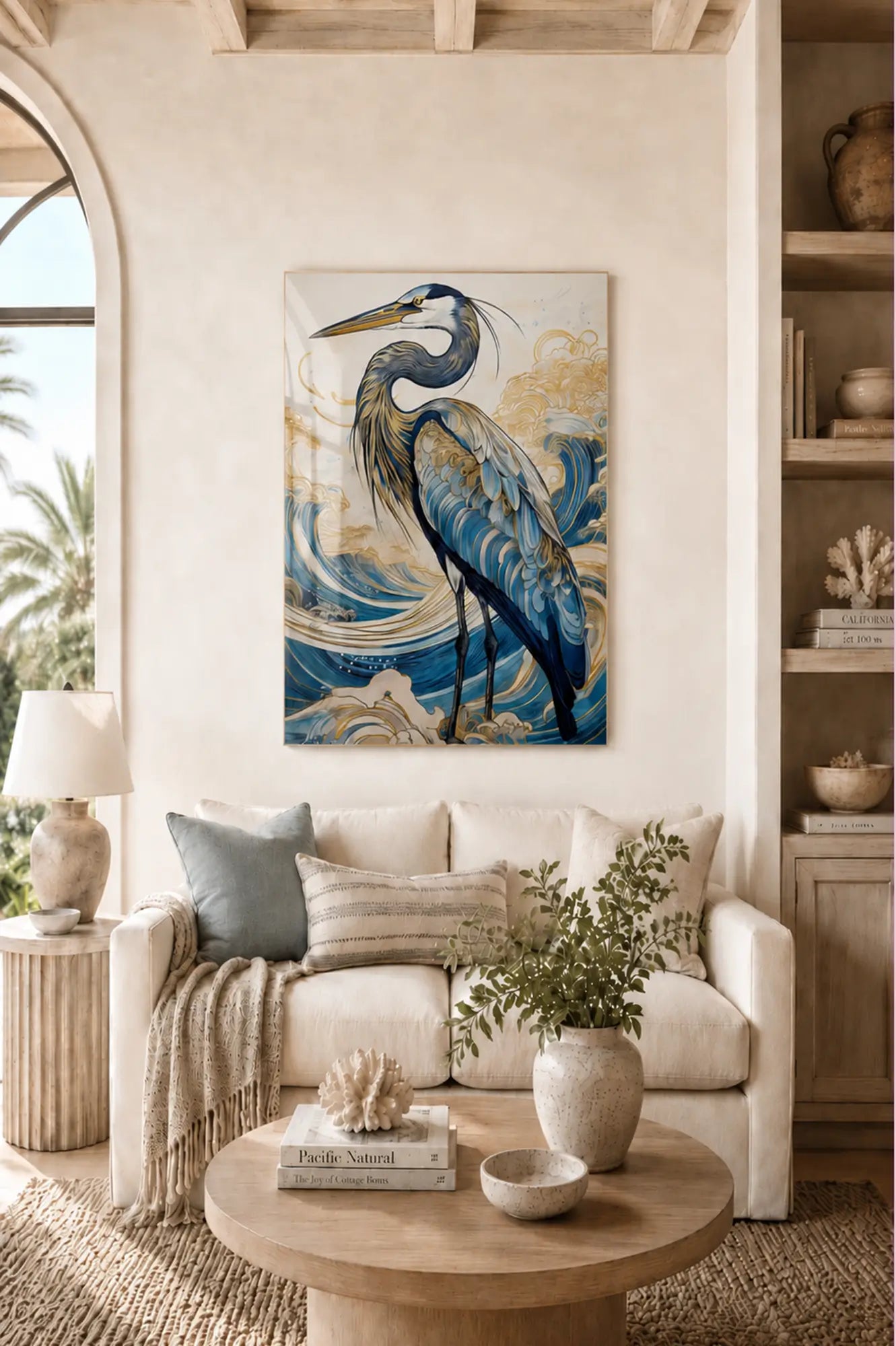 Coastal living room with a large glass print of a blue heron on the wall above a white sofa.