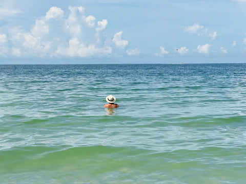 Person in sun hat floating in turquoise water for stunning beach photos with iPhone.