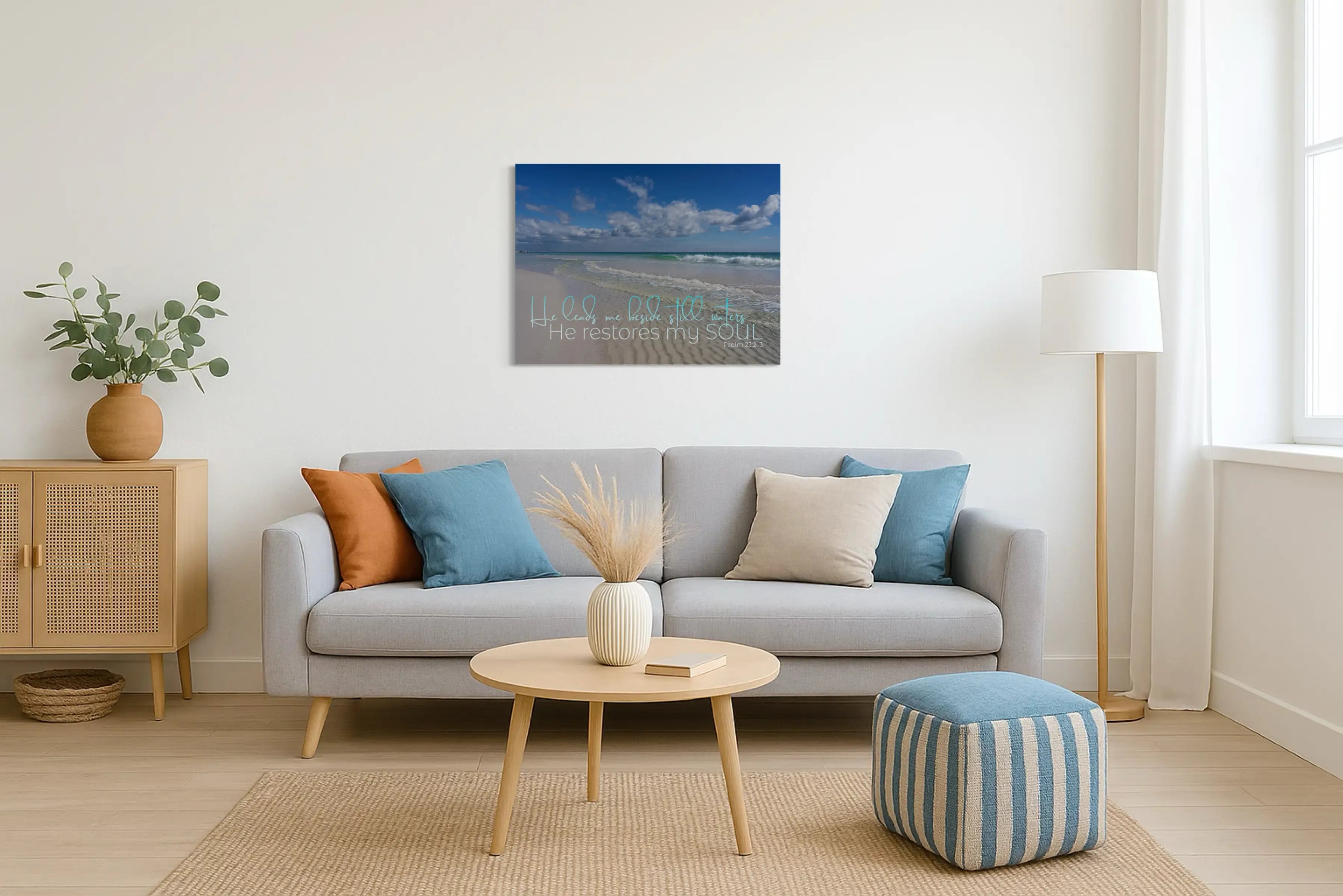 Inspirational Psalm 23 glass wall art hung in a bright coastal living room, pairing ocean hues with scripture for a peaceful, faith-filled space.