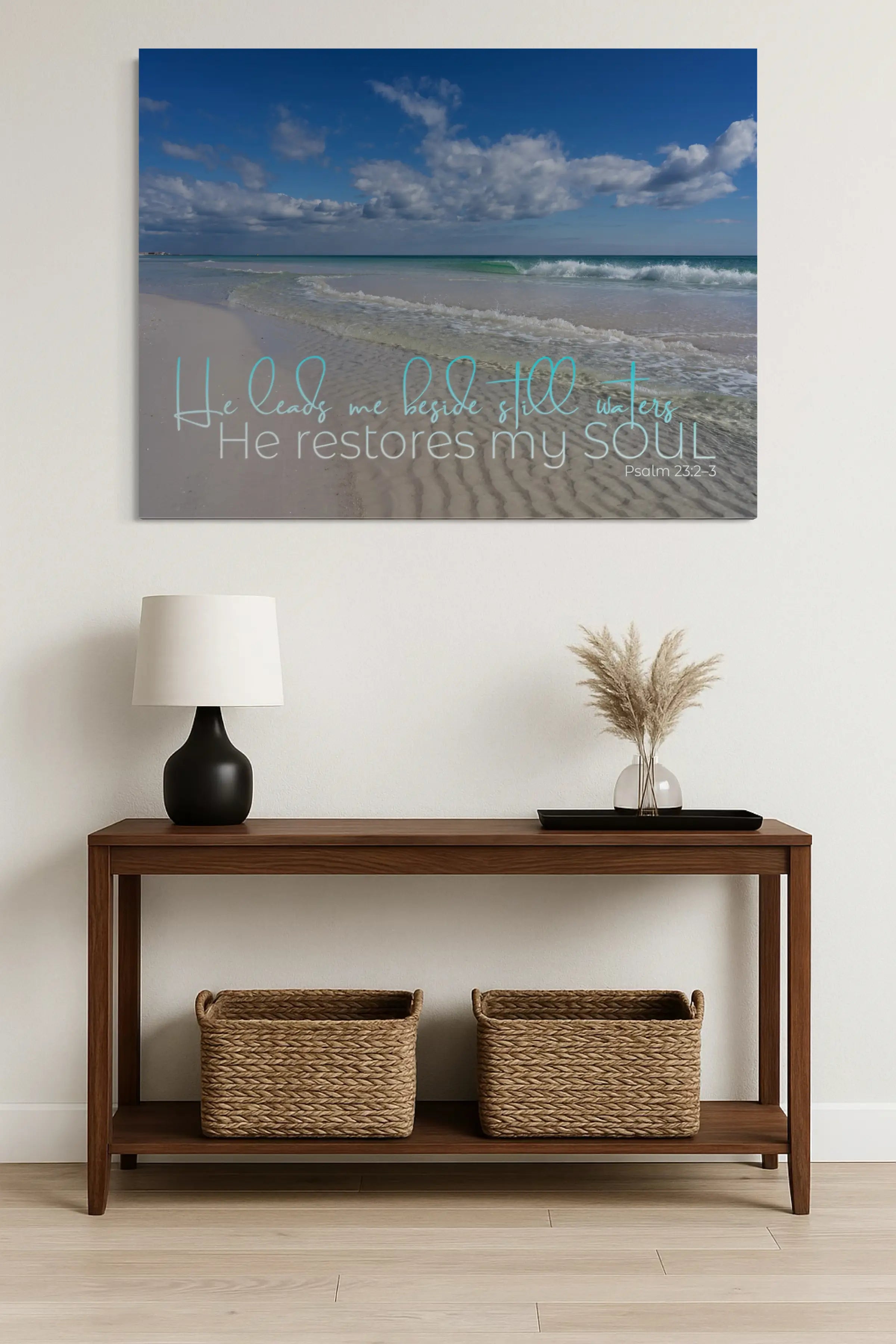 He leads me beside still waters, He restores my soul – Psalm 23 coastal glass print styled above a modern white entryway table with wicker baskets, creating a warm and welcoming first impression.