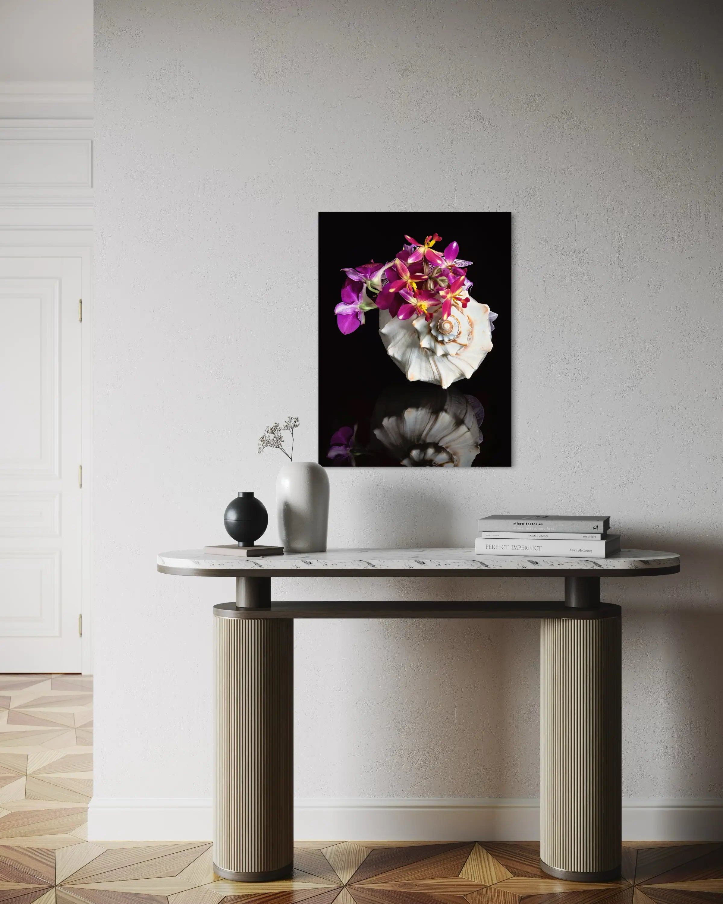 Coastal glass print of a triton shell filled with colorful orchids on a black reflective surface above side table